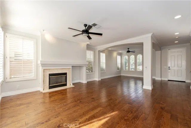 a kitchen with stainless steel appliances granite countertop a stove top oven a refrigerator a sink and white cabinets with wooden floors