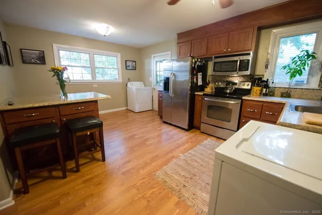 a kitchen with stainless steel appliances kitchen island granite countertop a refrigerator stove top oven and sink