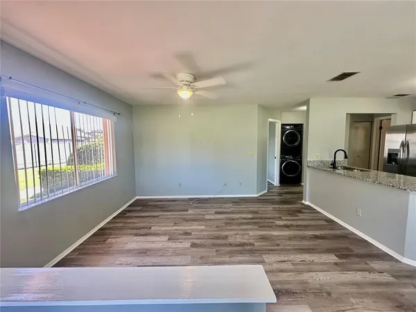 a view of an empty room with window and a kitchen