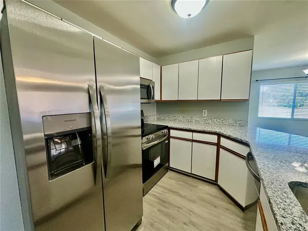 a kitchen with stainless steel appliances granite countertop a refrigerator a stove and a sink with wooden floor