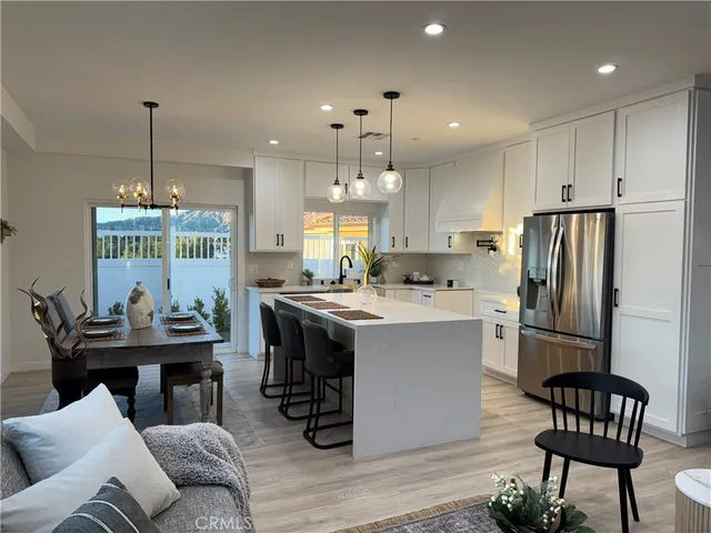 a kitchen with a refrigerator a sink dishwasher a dining table and chairs with wooden floor