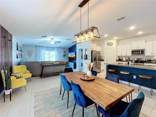 a view of a dining room and livingroom with furniture wooden floor a rug a rug a flat screen tv a rug a fireplace and a chandelier