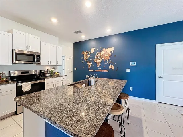 a kitchen with stainless steel appliances granite countertop a stove a sink dishwasher a microwave oven with a dining table and chairs