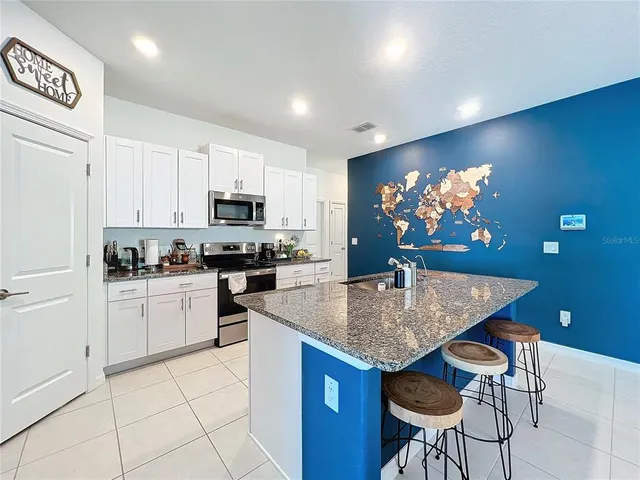 a kitchen with kitchen island granite countertop a sink a center island and cabinets