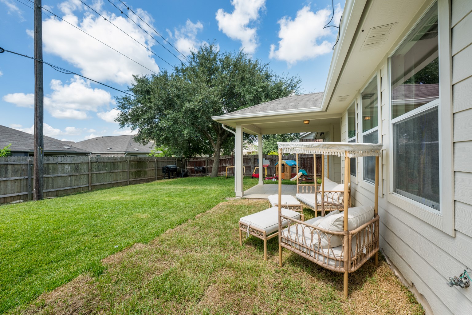 1391 Stone Rim Loop Buda, TX 78610 - Photo 26 of 35 A spacious, grassy backyard provides ample room for recreation and relaxation under a covered patio.
