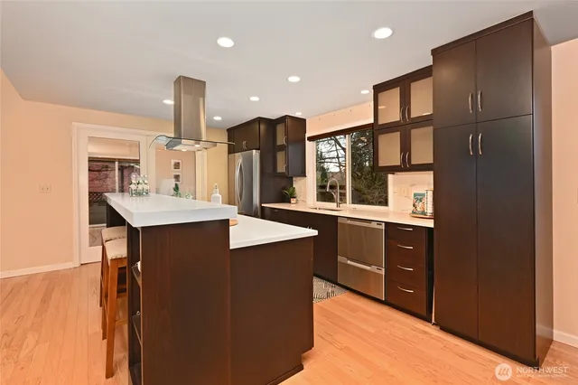 a kitchen with stainless steel appliances kitchen island granite countertop a refrigerator and a sink