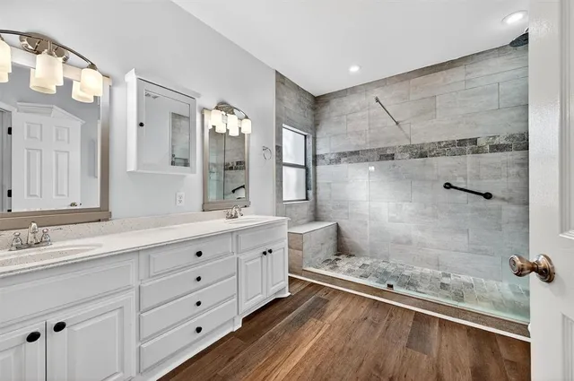 a spacious bathroom with a double vanity sink a mirror and a shower
