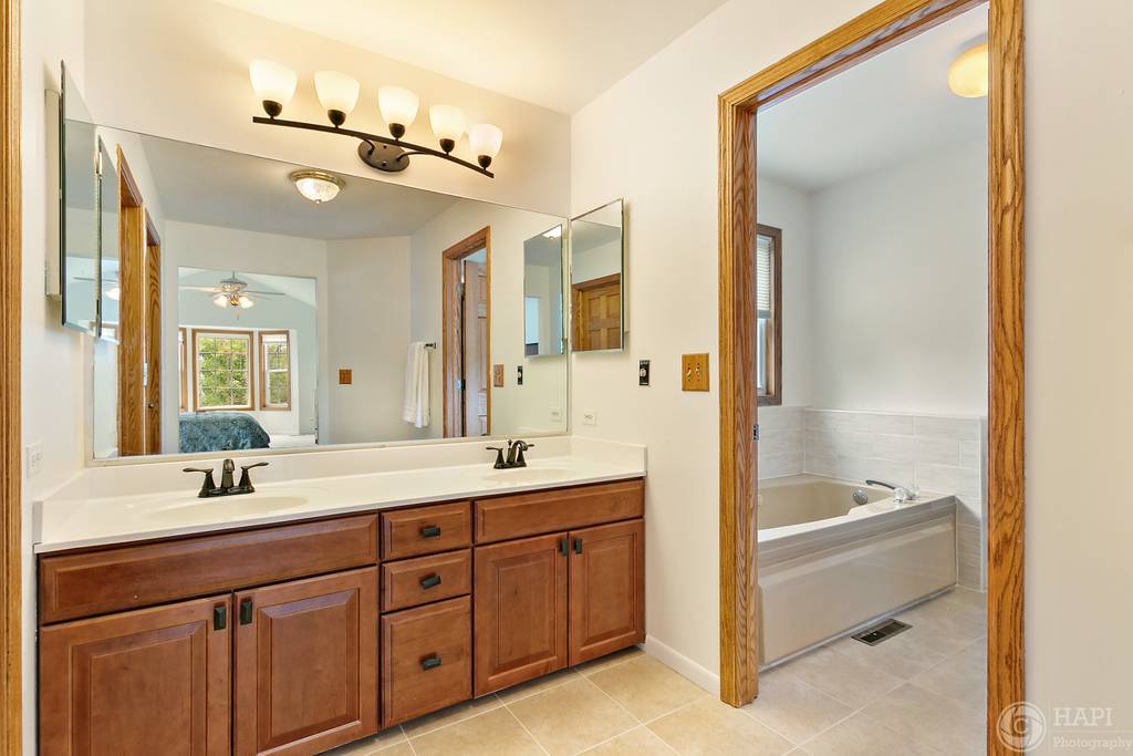 625 Red Bridge Road Lake Zurich, IL 60047 - Photo 14 of 27 a spacious bathroom with a double vanity sink a large mirror and a bathtub