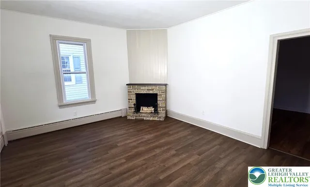 an empty room with wooden floor a fireplace and windows