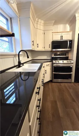 a kitchen with stainless steel appliances granite countertop a stove a sink and a microwave