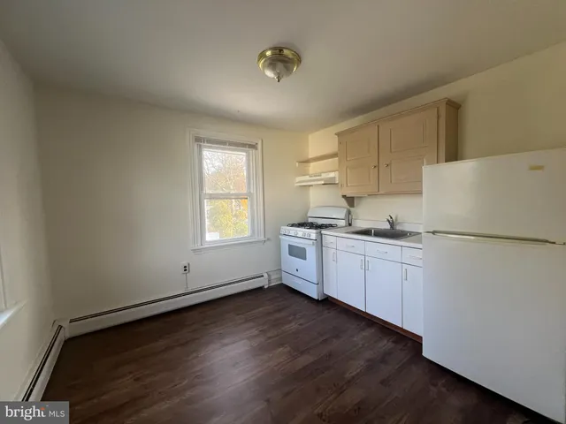 a kitchen with sink a refrigerator and white cabinets