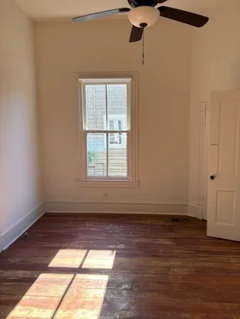 a view of an empty room with wooden floor and a window