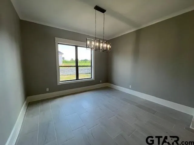 an empty room with chandelier fan and windows