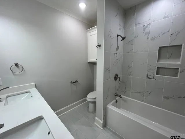 a bathroom with a granite countertop toilet a sink and bathtub