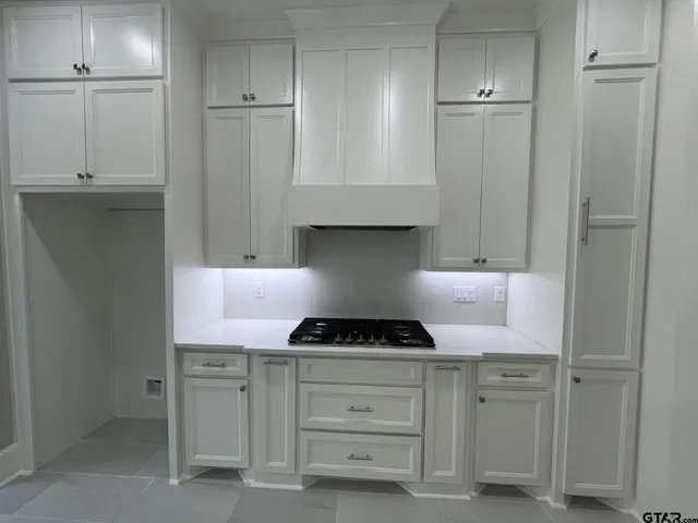 a kitchen with white cabinets and a stove