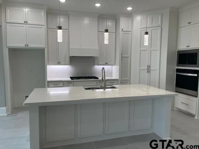 a kitchen with kitchen island a refrigerator and a stove top oven