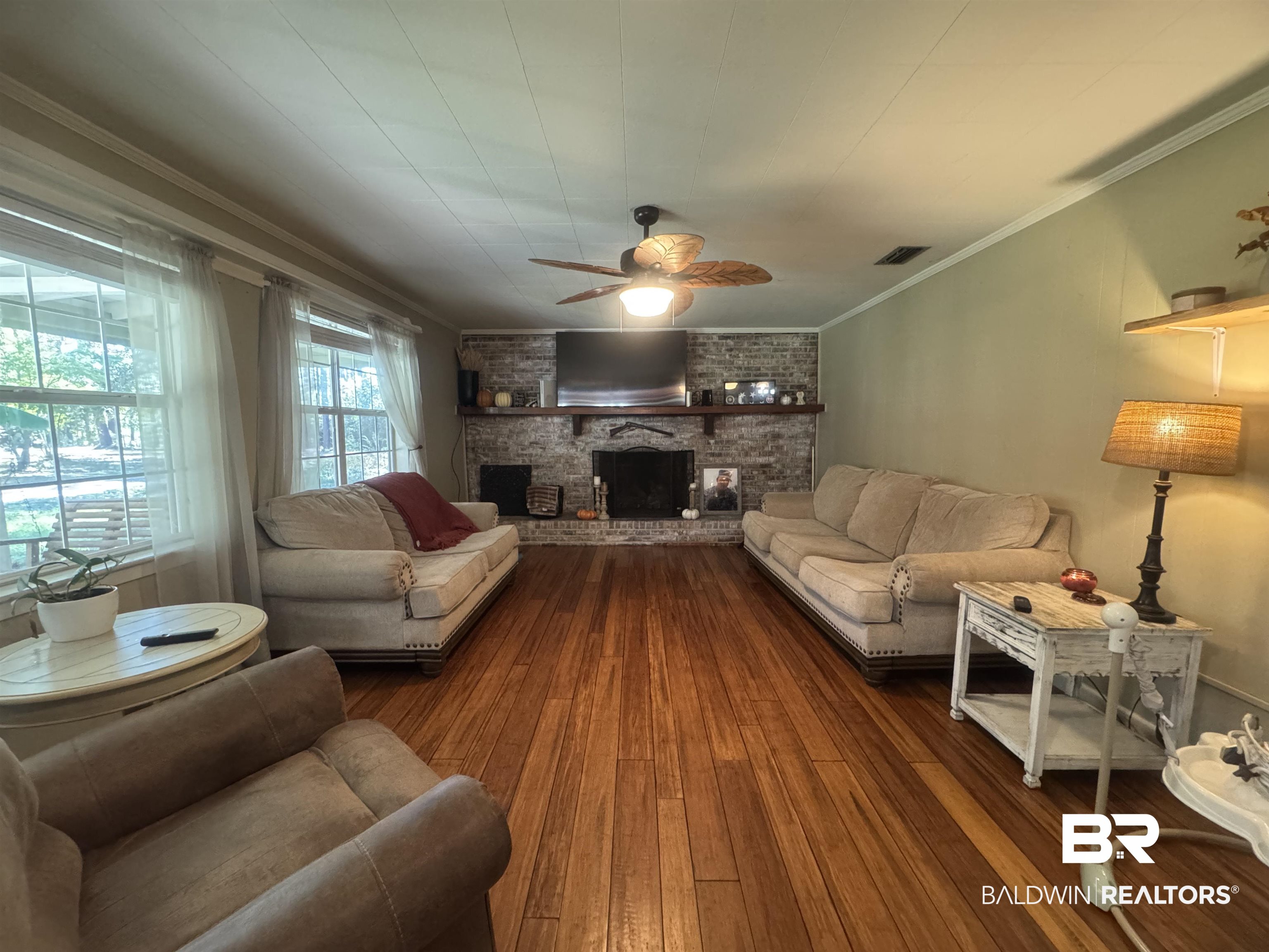 3097 Old Castleberry Road Brewton, AL 36426 - Photo 2 of 49 Living room featuring dark wood-type flooring, a brick fireplace, crown molding, and ceiling fan