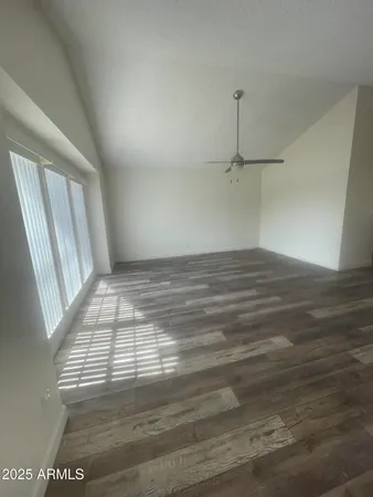 a view of empty room with wooden floor and fan