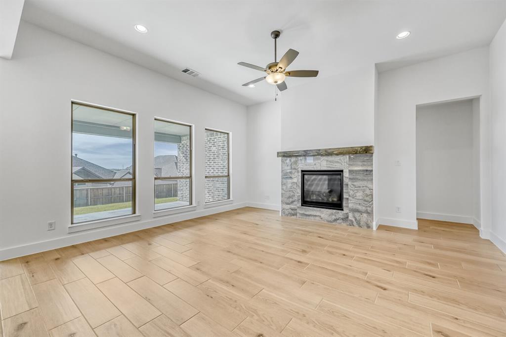 147 Derrett Lane Rhome, TX 76078 - Photo 3 of 28 Unfurnished living room featuring a ceiling fan, wood finish floors, recessed lighting, and a glass covered fireplace