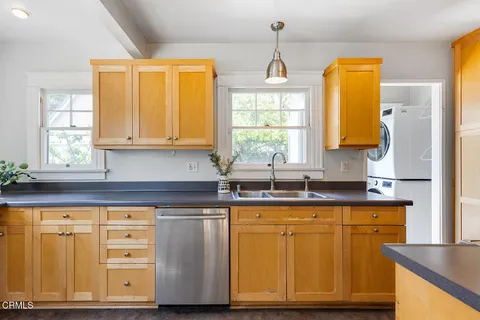 a kitchen with stainless steel appliances granite countertop a sink a window and cabinets