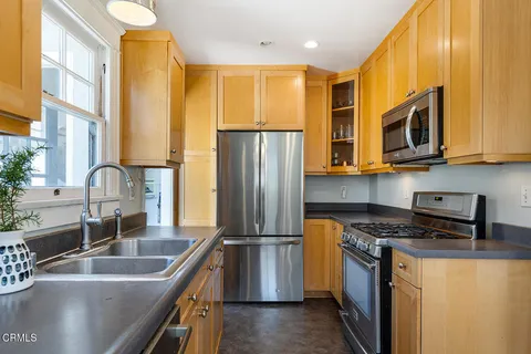 a kitchen with stainless steel appliances granite countertop a sink a stove and a refrigerator