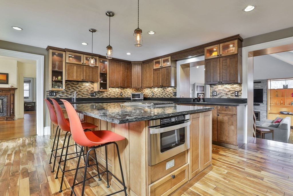 630 Brush Hill Road Milton, MA 02186 - Photo 13 of 41 a kitchen with stainless steel appliances granite countertop a stove top oven a sink a dining table and chairs with wooden floor