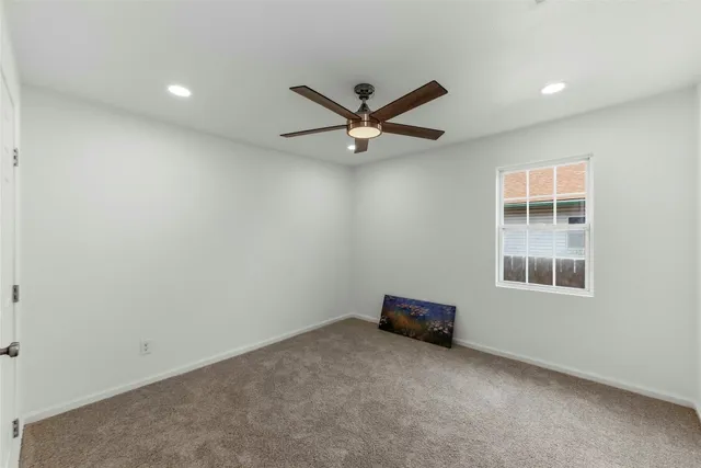 an empty room with a ceiling fan and window