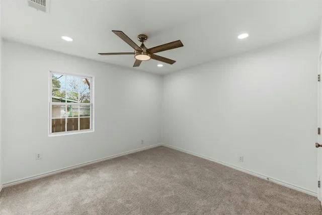 an empty room with a window and a ceiling fan