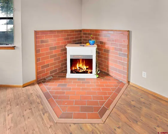a view of an empty room with wooden floor and a fireplace