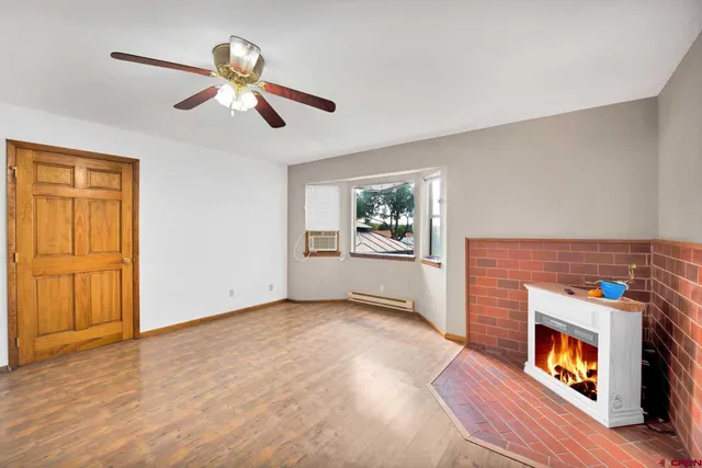 an empty room with windows fireplace and wooden floor