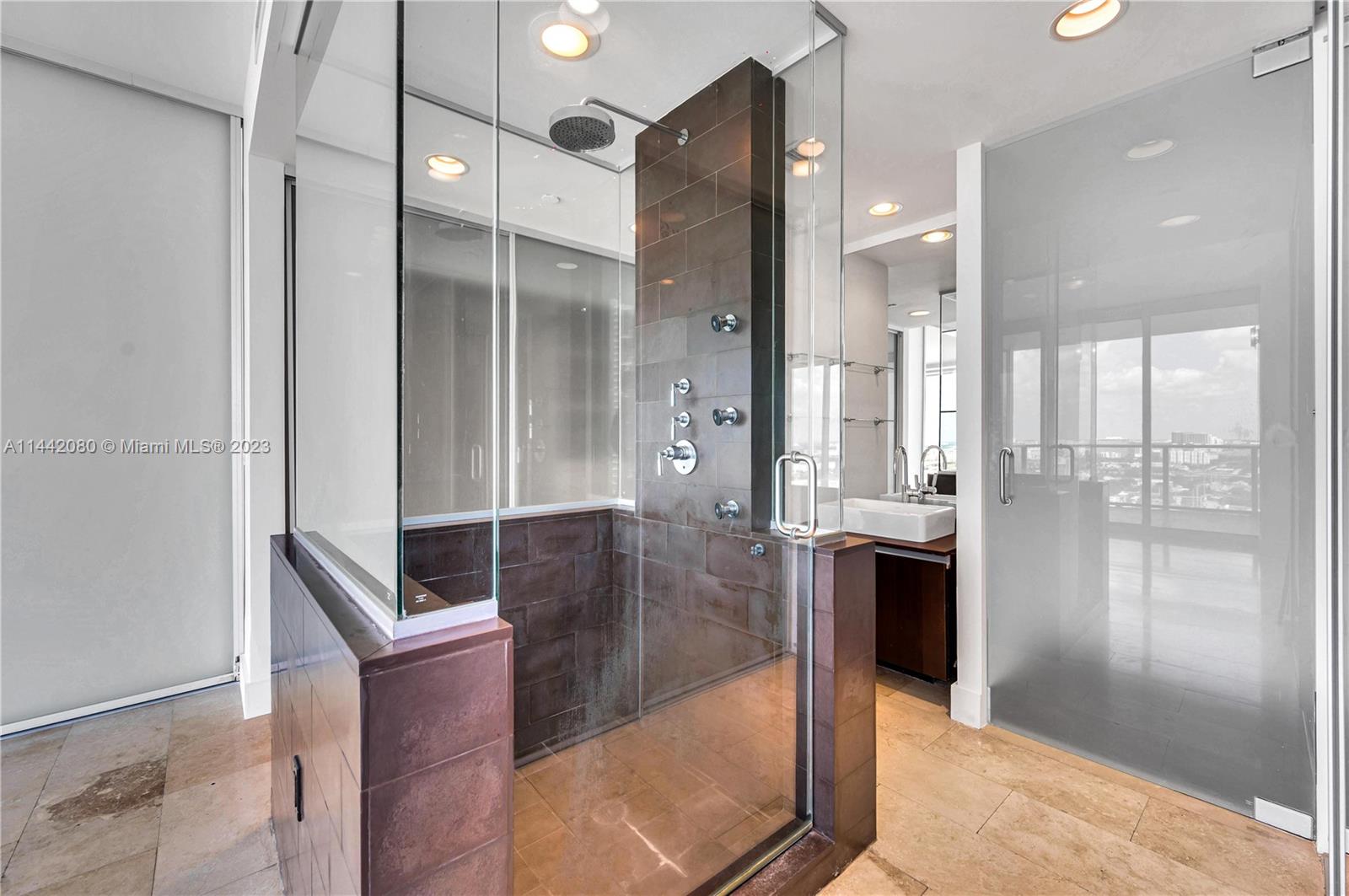 1040 Biscayne Boulevard, Unit 2107 Miami, FL 33132 - Photo 19 of 50 a bathroom with a glass shower door a sink and a mirror