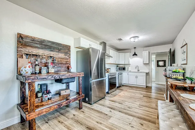 a kitchen with stainless steel appliances wooden floor and chairs