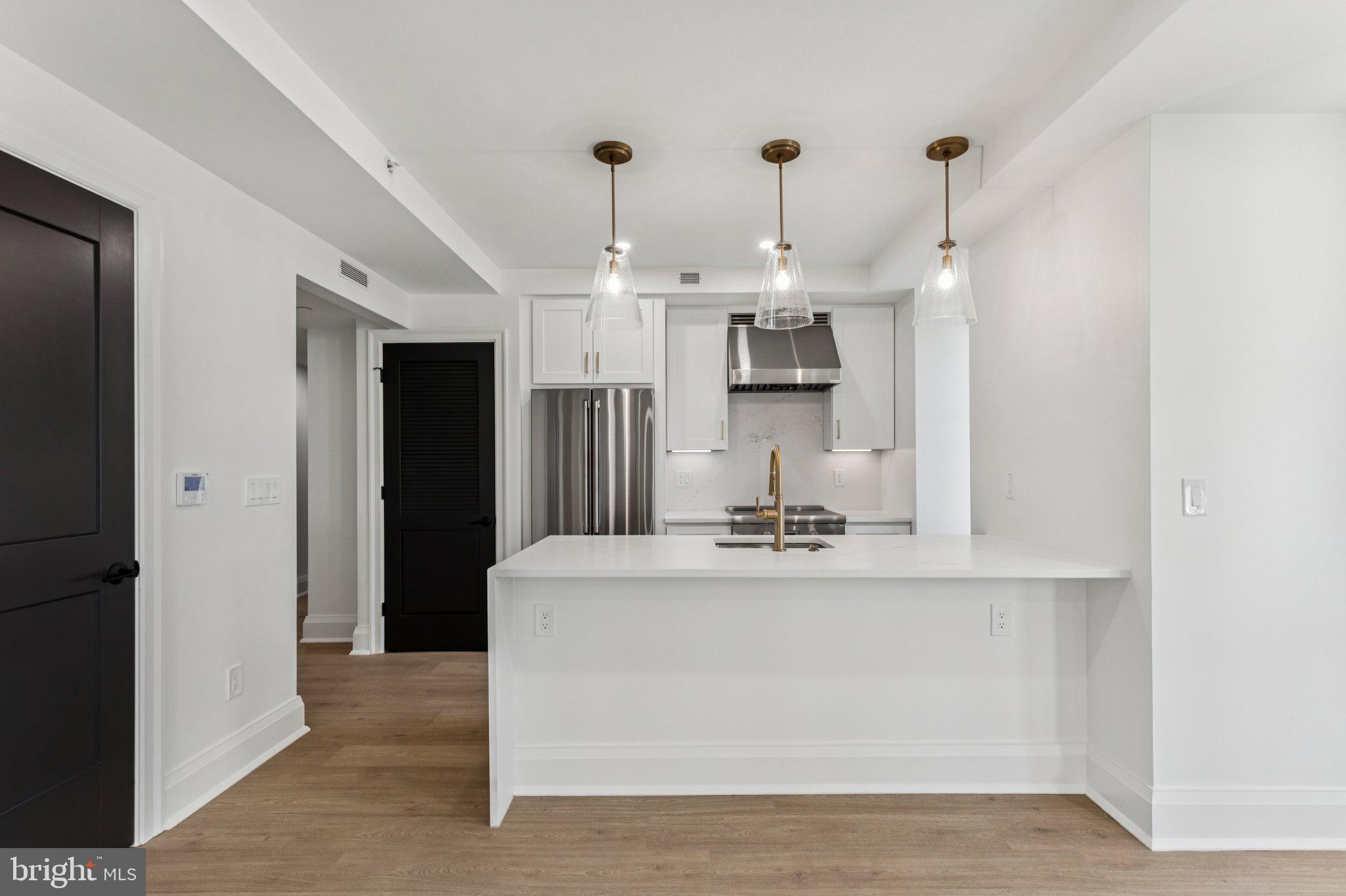 135 South 19th Street, Unit 308 Philadelphia, PA 19103 - Photo 6 of 24 a large white kitchen with kitchen island a sink stainless steel appliances and cabinets