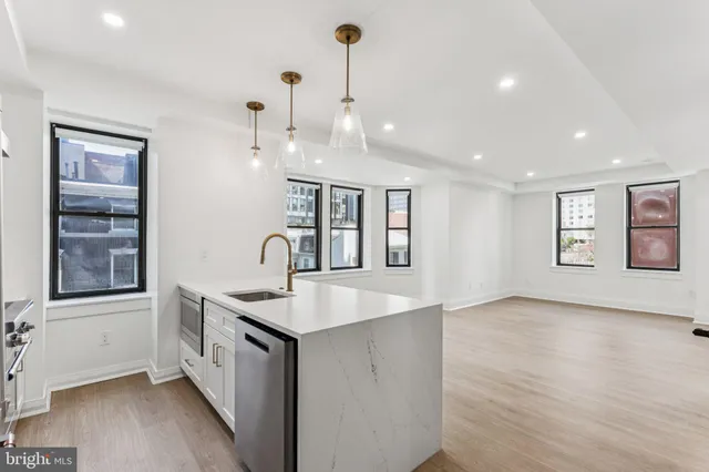 a view of a kitchen island a sink wooden floor and a living room