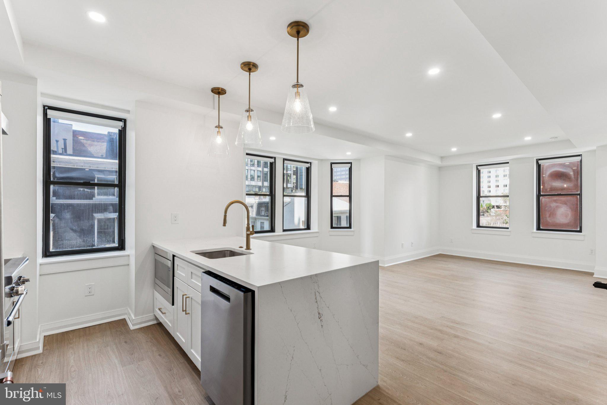 135 South 19th Street, Unit 308 Philadelphia, PA 19103 - Photo 9 of 24 a view of a kitchen island a sink wooden floor and a living room