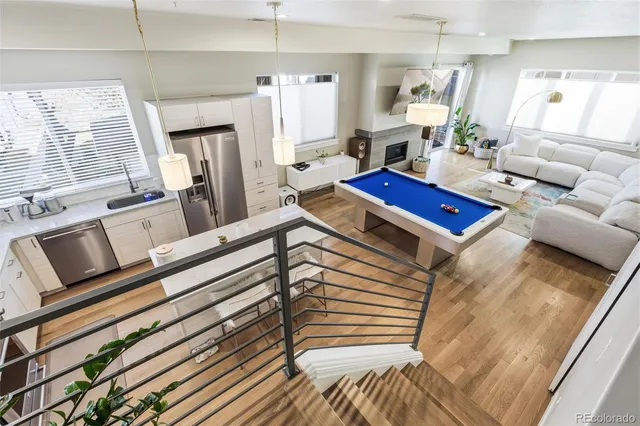 a living room with furniture a fireplace kitchen view and a large window
