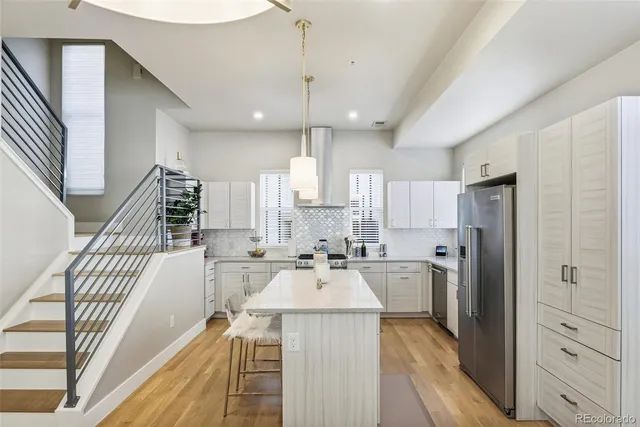 a large kitchen with kitchen island a large window a sink stainless steel appliances and cabinets