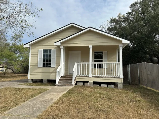 a view of a house with a yard and wooden fence