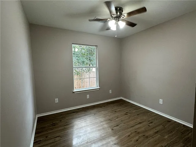 an empty room with wooden floor and a ceiling fan