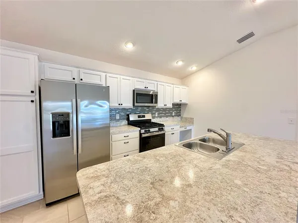 a kitchen with granite countertop a refrigerator and a stove top oven