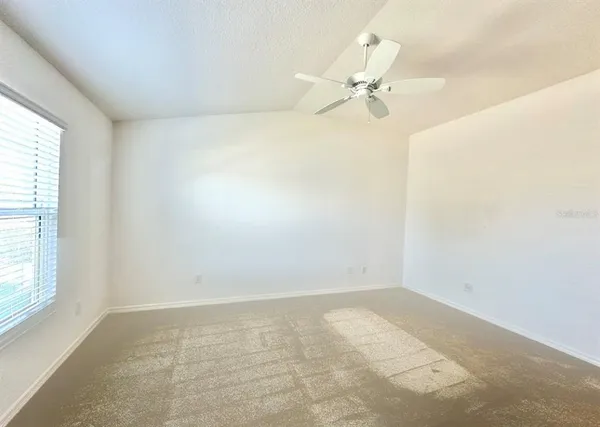 an empty room with a window and a fan