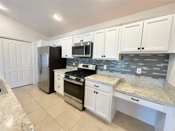 a kitchen with granite countertop a refrigerator stove and microwave