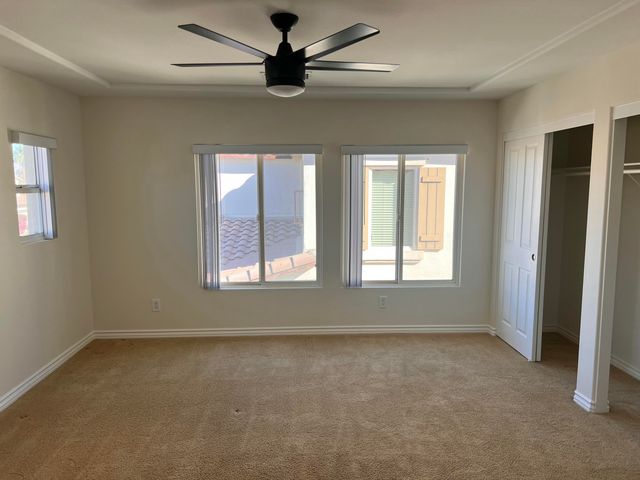 en empty room with windows and ceiling fan
