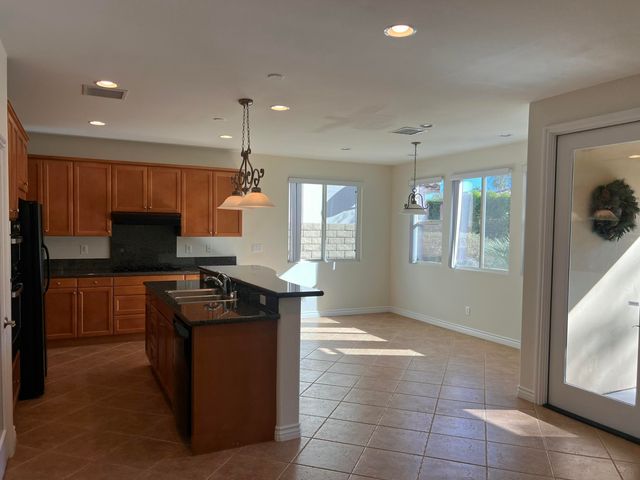 a kitchen with kitchen island granite countertop a refrigerator and a sink