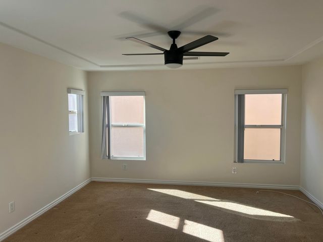 an empty room with windows and fan