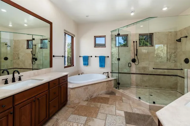 a bathroom with a granite countertop shower sink vanity and mirror