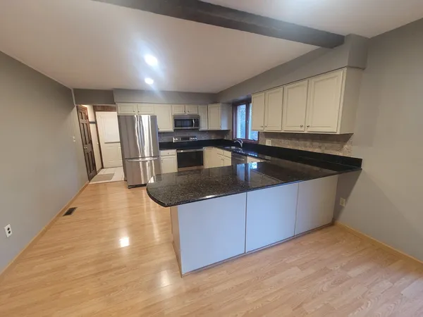 a kitchen with stainless steel appliances granite countertop a sink window and cabinets