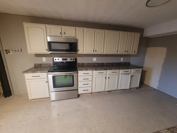 a kitchen with stainless steel appliances granite countertop a stove a microwave and a refrigerator