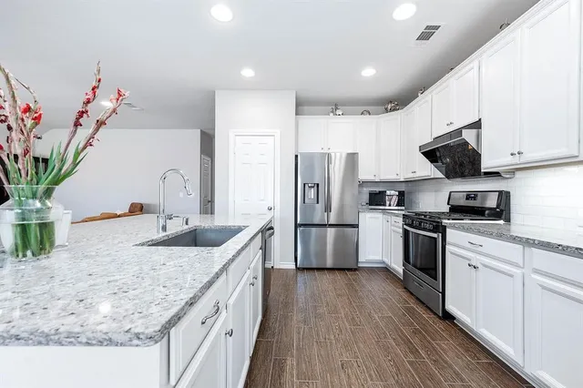 a kitchen with stainless steel appliances granite countertop a sink a stove and a refrigerator