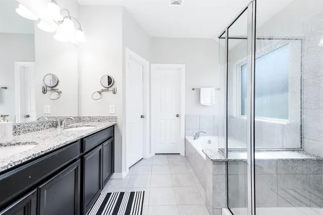 a spacious bathroom with a granite countertop sink a mirror and shower